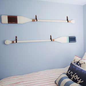 A marine themed bedroom showcases two oar paddles on the wall. 
Our Leather Wall Straps are used to hang oar paddles on the wall, the handle of the oar fits through the loop of the strap once installed.