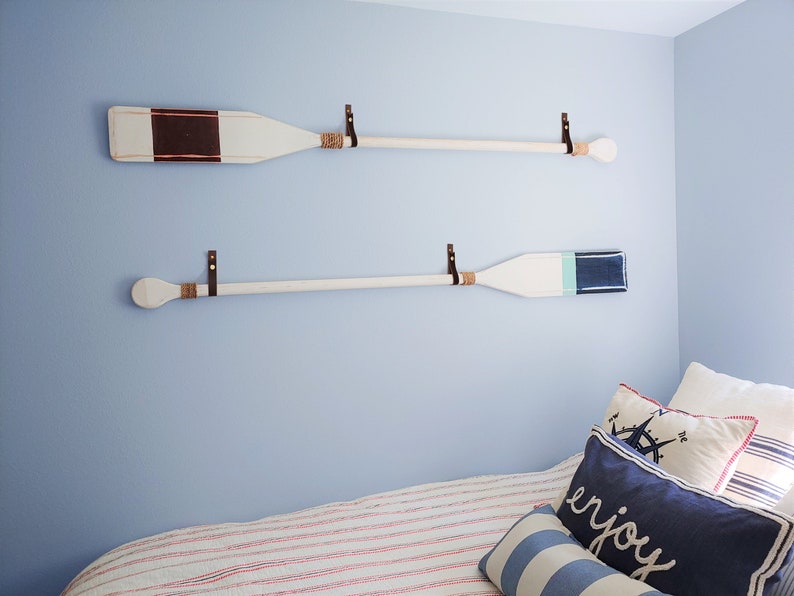 A marine themed bedroom showcases two oar paddles on the wall. 
Our Leather Wall Straps are used to hang oar paddles on the wall, the handle of the oar fits through the loop of the strap once installed.
