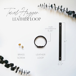 Flat lay photo of Keyaiira Leather Loop Towel Hanger set including a leather strap, brass screws, and a metal ring arranged on a white background with eucalyptus branches. Text overlay shows dimensions and product details in a modern, minimal layout.