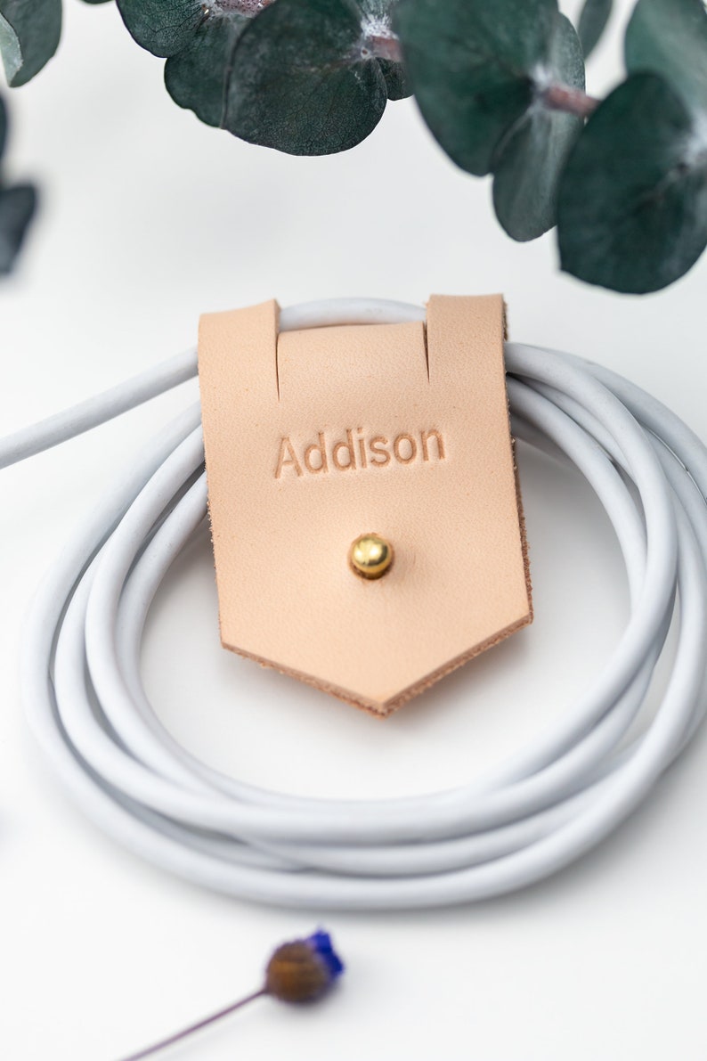 Closeup of Large Leather Cord Holder displayed on a white background wrapped around a cord. Imprinted personalization.