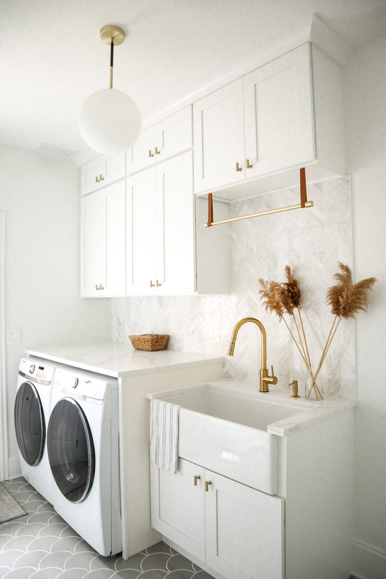 A laundry rack installed with Suspension Straps under a cabinet in a laundry room above a sink.