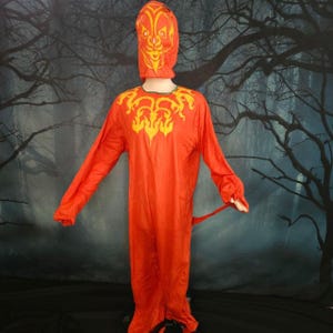 May include: A bright orange full-body costume featuring a hood with a stylized yellow face print. The chest area displays a decorative yellow flame-like pattern. The garment has long sleeves and a loose fit, covering the entire body from head to toe.