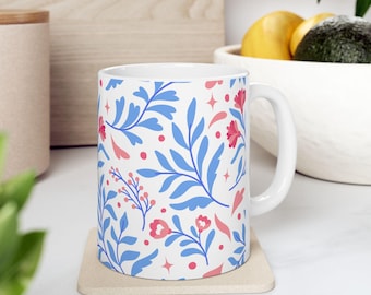 Czerwony ceramiczny kubek z kwiatowym wzorem, delikatne niebieskie liście na białym tle