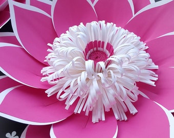 Puede incluir: Una gran flor de papel hecha a mano, con pétalos de color rosa vibrante y detalles en blanco. El centro de la flor es una disposición detallada de tiras de papel blanco, con un centro rosa más pequeño. Diseño floral decorativo.