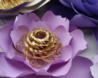 Puede incluir: Una gran flor de papel morada con un centro dorado. La flor está hecha de múltiples capas de papel y tiene una textura delicada y rizada.