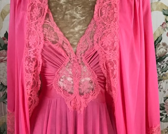 May include: A pink sheer nightgown with a lace trim and a matching robe. The nightgown has a V-neckline and a gathered bodice. The robe has long sleeves and a shawl collar.