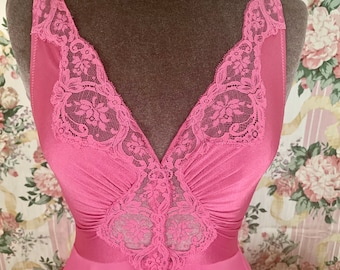 Op de afbeelding: Een roze, mouwloze nachtjapon met kantversiering rond de halslijn en een kantpaneel in het midden van het bovenstuk.