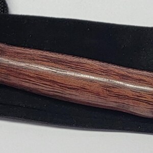 Pode incluir: Um rasgador de costura com cabo de madeira e detalhes em metal prateado, em um saco preto. O cabo &eacute; de cor marrom escuro, e o rasgador tem uma ponta com uma pequena conta vermelha.