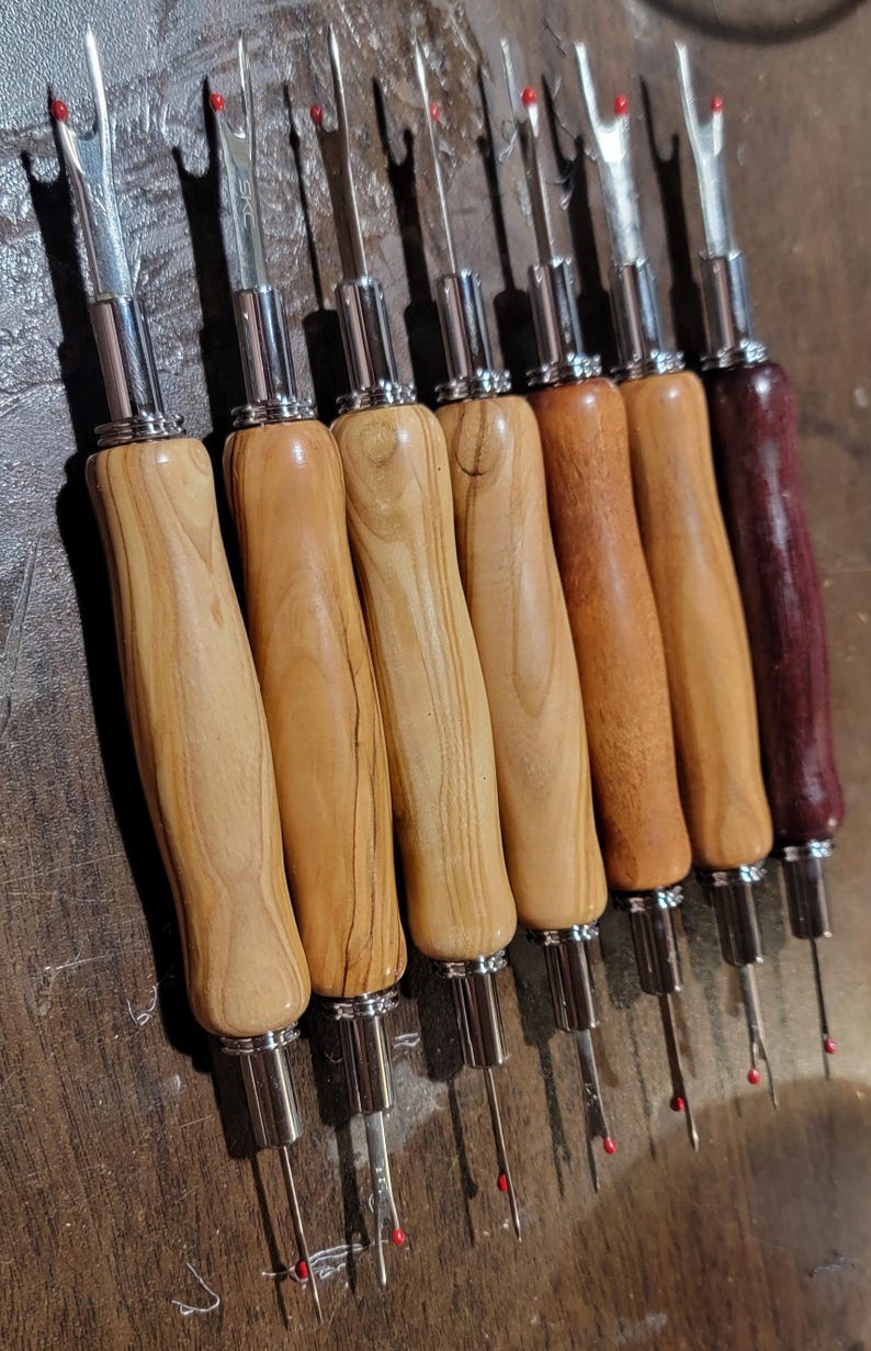 Pode incluir: Uma cole&ccedil;&atilde;o de desfibradores com cabos de madeira em v&aacute;rios tons de castanho claro e bord&ocirc; escuro. Os desfibradores t&ecirc;m l&acirc;minas de metal prateado e pontas vermelhas, ideais para projetos de costura e artesanato.