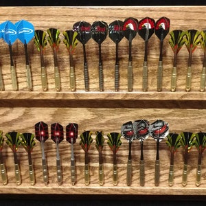May include: A wooden dart holder with two rows of darts. The darts are arranged in rows and are of various colours and designs. The holder is made of dark wood with a natural grain.