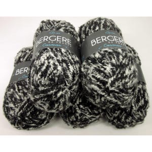 May include: Several skeins of black and white speckled yarn. Each skein has a label that reads "BERGER DE FRANCE Cosmos". The yarn appears to be a bulky weight, suitable for knitting or crocheting projects. The yarn is a mix of black and white fibers.