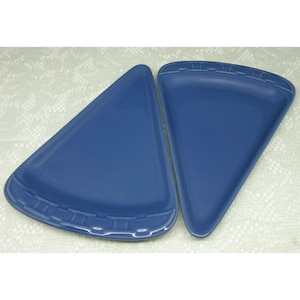 May include: Two blue triangular plates. The plates are a solid blue color and have a slightly raised edge with a decorative pattern on one side. The plates are likely for serving pizza or other similar foods.