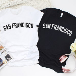 May include: Two t-shirts, one white and one black, with the text "SAN FRANCISCO" printed in black on the white shirt and white on the black shirt.