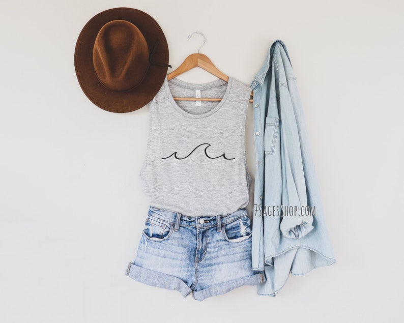 May include: A gray tank top with a simple black wave design. The tank top is styled with denim shorts and a light blue denim jacket.