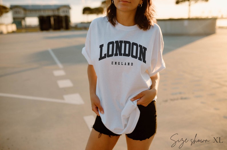 May include: White t-shirt with a black graphic that says "LONDON ENGLAND" in a collegiate font. Size shown is XL.