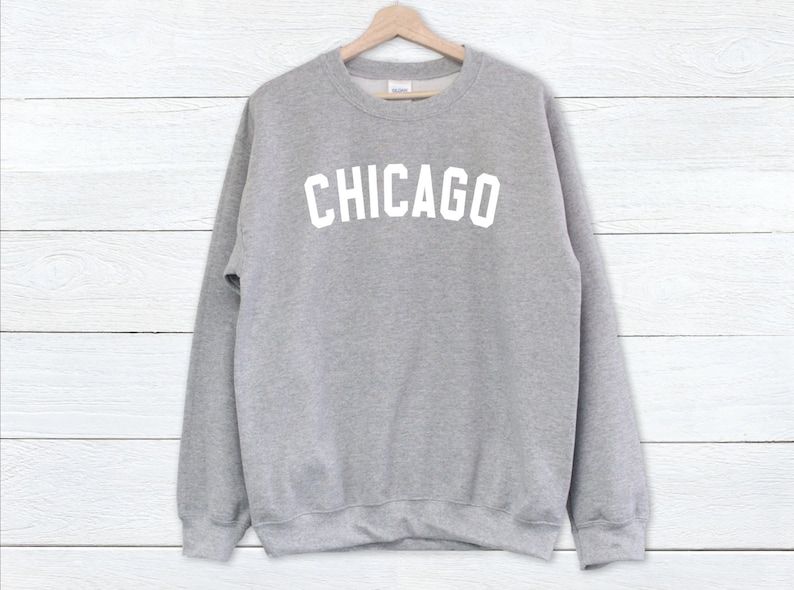 Puede incluir: Una sudadera gris con la palabra "CHICAGO" impresa en blanco en la parte delantera.