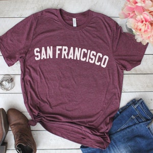 May include: A maroon t-shirt with the text "SAN FRANCISCO" in white letters.
