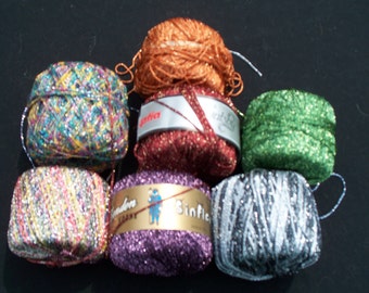 May include: Six spools of sparkly yarn in various colors, including green, purple, silver, and multi-colored. The yarn is labeled "Sinflo" and "Gaffa".