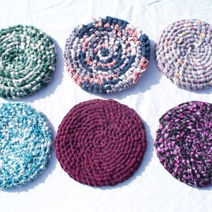May include: Six round crocheted floor cushions in various colors and patterns. The cushions are made from recycled materials and are perfect for adding a touch of bohemian style to any room.