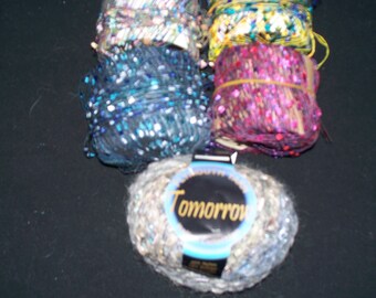 May include: Four spools of sparkly yarn with sequins, one spool is labeled "Tomorrow".