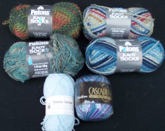 May include: Assortment of yarn skeins in various colors and patterns, including blue, green, red, and orange. The yarn is labeled "Patons Kroy Socks" and "Cascade".