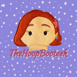 May include: A felt applique of a cartoon character with brown hair, a pink flower, and a blue earring. The character has a light brown skin tone and large eyes. The text "The Hoop Booteek" is visible below the character.