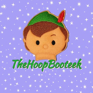 May include: Embroidered felt patch of Peter Pan with a green hat, brown hair, and a red feather. The patch is on a purple background with white stars. The text "The Hoop Booteek" is below the patch.