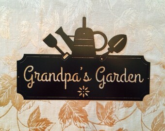 May include: Black metal sign with the text "Grandpa's Garden" and a silhouette of a watering can and gardening tools.