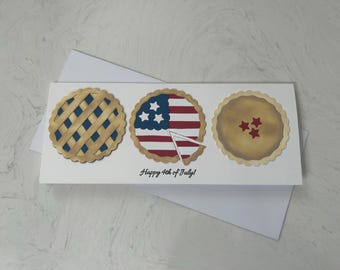 May include: A white card with three pie crusts decorated with an American flag, a lattice pattern, and red stars. The card reads "Happy 4th of July!"