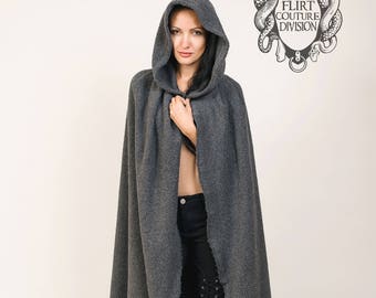May include: A long, hooded gray cape with a textured appearance. The cape is open in the front, revealing black pants and boots. The image includes a logo with the text "FLIRT COUTURE DIVISION".