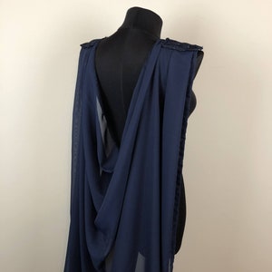 May include: A navy blue chiffon cape with a lace trim. The cape is draped over a mannequin and has a deep V-neckline.
