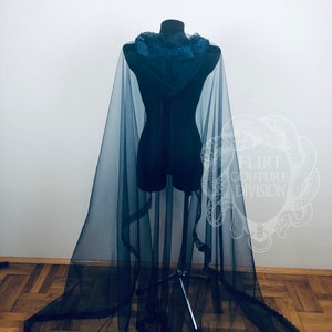 May include: A black sheer cape with a hood and lace trim. The cape is draped over a mannequin and has a long train.