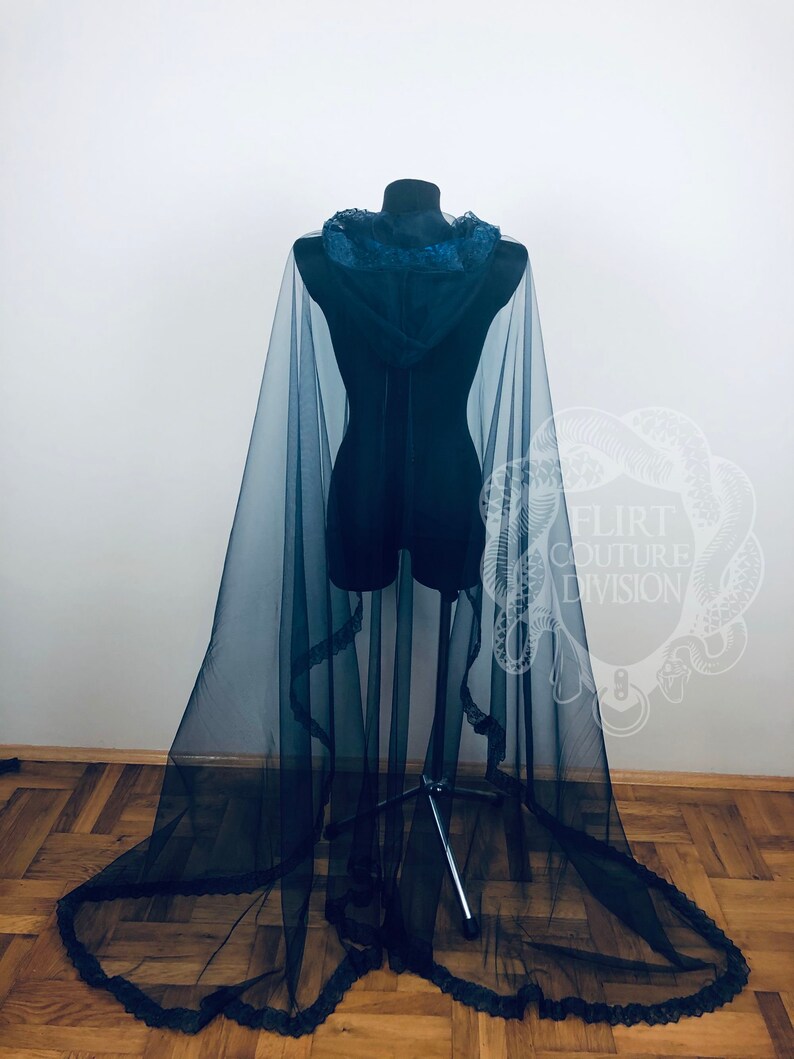 May include: A black sheer cape with a hood and lace trim. The cape is draped over a mannequin and has a long train.
