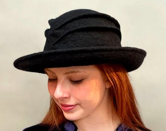 May include: A black felt hat with a wide brim and a unique folded design on the crown.