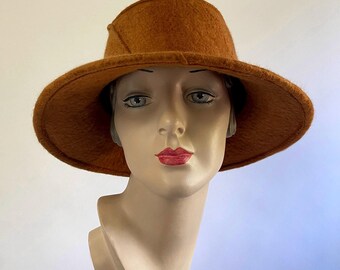 May include: A wide-brimmed hat made of brown felt. The hat has a slightly angled brim and a simple, rounded crown.