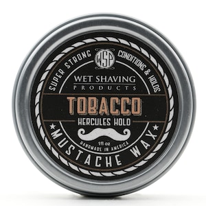 May include: A silver tin with a black label that says "SUPER STRONG WSP CONDITIONS & HOLDS WET SHAVING PRODUCTS TOBACCO HERCULES HOLD 1fl oz MUSTACHE WAX* HANDMADE IN AMERICA".