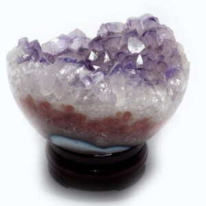 Peut inclure: Une géode d'améthyste violette avec un extérieur en agate naturel. La géode est sur un support en bois.
