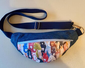 May include: A denim fanny pack with a zipper closure and a blue adjustable strap. The front of the pack features a colorful print of horse faces.
