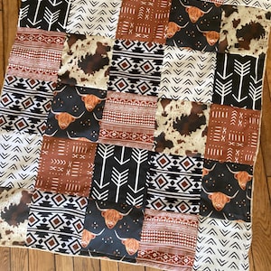 May include: A patchwork quilt with a brown, white, and black color scheme. The quilt features a variety of geometric patterns and images of Highland cattle.