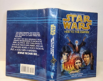 May include: A book cover for the Star Wars novel "Heir to the Empire" by Timothy Zahn. The cover features a blue background with a depiction of Luke Skywalker, Han Solo, Princess Leia, and a mysterious figure with a long white beard. The text "Star Wars" is in gold lettering and the title "Heir to the Empire" is in white lettering.