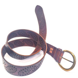 May include: A brown leather belt with a decorative floral pattern and a brass buckle.