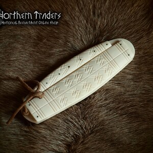 May include: A white bone folding knife with a carved geometric pattern. The knife is closed and tied with a brown leather cord.