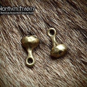 May include: Two gold-colored metal toggles with a rounded top and a loop on the bottom. The toggles are on a brown furry surface.