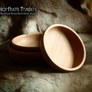 Könnte beinhalten: Drei kleine, hellfarbene Holzschalen sind auf einer strukturierten, braunen Oberfläche gestapelt. Die Schalen haben ein einfaches, rundes Design mit glatter Innenseite. Das Bild zeigt auch den Text "Northern Traders Historical Reenactment Online Shop".
