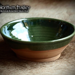 May include: A handcrafted ceramic bowl with a green glazed interior and rim, and a natural clay-coloured exterior. The bowl has a wide, shallow shape, suitable for serving food. The "Northern Traders" logo is visible in the upper left corner.