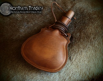 May include: A brown leather water bottle with a wooden stopper and a leather strap. The bottle is on a furry surface.