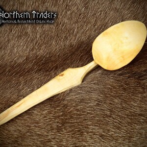 Könnte beinhalten: Ein Holzlöffel mit hellbrauner Farbe und einer glatten, abgerundeten Schüssel. Der Löffel ist handgefertigt und hat ein schlichtes, elegantes Design.