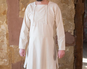 Op de afbeelding: Een witte linnen tuniek met lange mouwen en een koordgesloten halslijn. De tuniek heeft een eenvoudige, klassieke stijl en is gemaakt van een lichtgewicht stof.