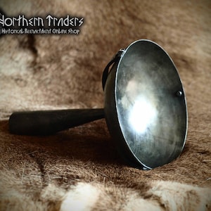 May include: A metal ladle with a rounded bowl and a long, dark handle. The ladle is made of a shiny, silver-coloured metal and appears to be handcrafted. The image includes the text "Northern Traders Historical Reenactment Online Shop".