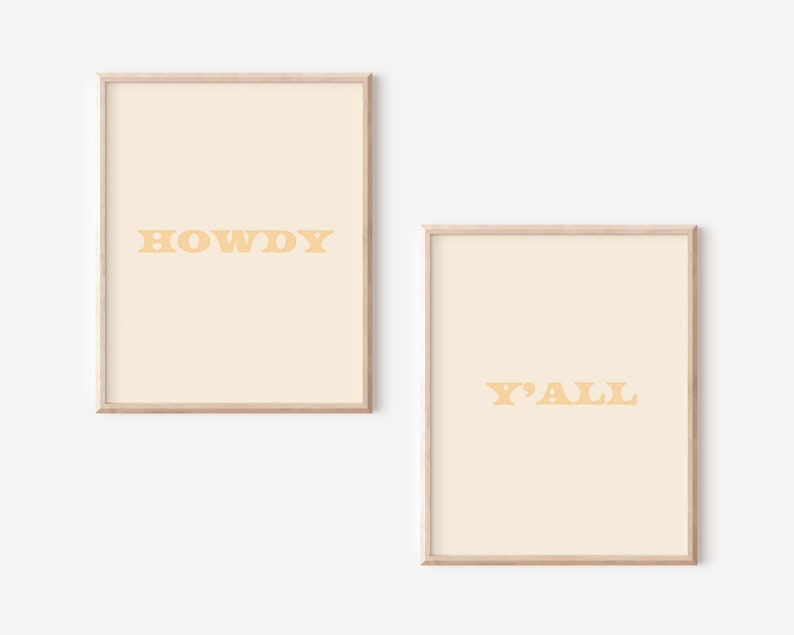 May include: Two framed prints with a light beige background and yellow text. The first print says "HOWDY" and the second print says "Y'ALL".